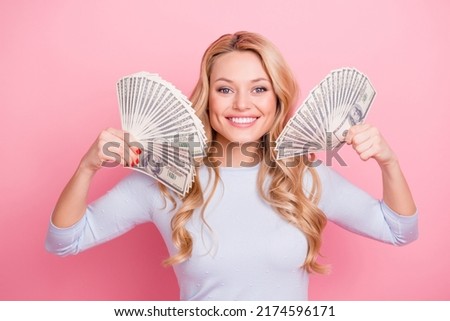 Photo of pretty sweet lady dressed blue shirt smiling holding two cash fans isolated pink color background