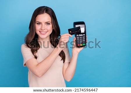Photo of young charming female using terminal and nfc card to pay her groceries isolated on blue color background