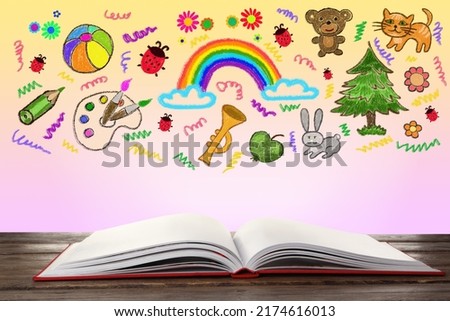 Open book on wooden table against wall with drawings