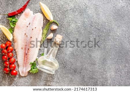 Fresh raw white fish fillet Pangasius with spices and lemon on a stone background with copy space for your text