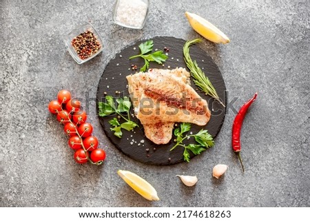 Baked white fish fillet Pangasius with spices and lemon on a stone background Royalty-Free Stock Photo #2174618263