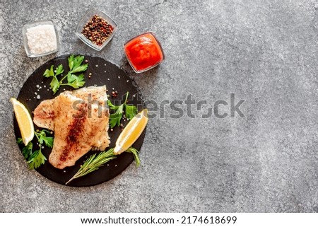 Baked white fish fillet Pangasius with spices and lemon on a stone background with copy space for your text