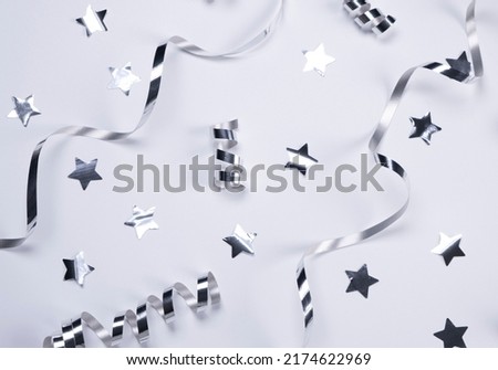 White background with a silver serpentine and stars. concept of celebrating a birthday,newborn , party or anniversary in silver tones Royalty-Free Stock Photo #2174622969