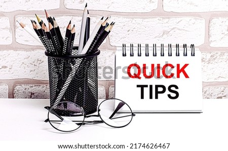 A workplace in the house with glasses, pencils in a stand and a notebook with text QUICK TIPS on a brick wall background. Home office. Scandinavian style