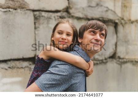 man dad having quality time with their kid daughter girl nine year old on his back. happy father playing with child. real life authentic day-to-day fatherhood moments. fatherly love care and affection
