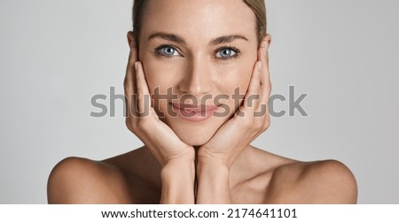 Skin care. Beautiful woman with healthy facial skin touching hands moisturized face skin, on light grey background. High quality Royalty-Free Stock Photo #2174641101