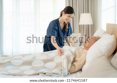 Asian nurse in nursing home support old man for sleeping on the bed in patient room Royalty-Free Stock Photo #2174641587