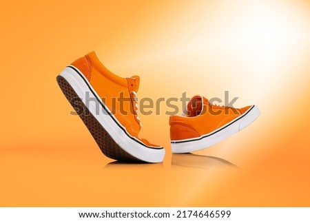 Sunny day. Modern unisex footwear, sneakers isolated on orange background. Fashionable stylish sports casual shoes. Creative minimalistic layout with footwear. Mock up for design, ad for shoe store Royalty-Free Stock Photo #2174646599