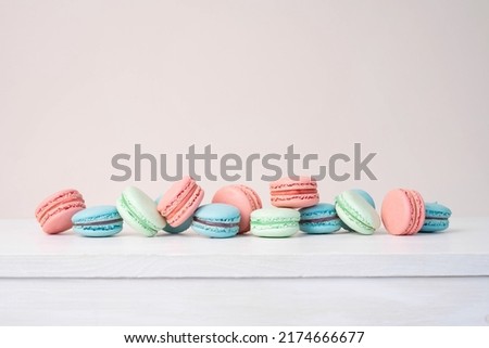 Pink, blue and mint macaron cookies on a beige background. 