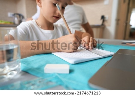 Male kid scribbling in his notepad with pencil