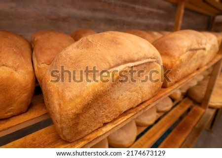 Close-up of freshly baked bread on wooden shelves. Production of bakery products