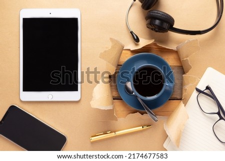 Tablet and cup of coffee with stationary supplies at paper background texture. Office business concept idea