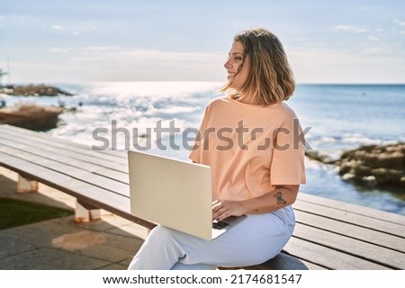 Young hispanic woman smiling confident using laptop at seaside Royalty-Free Stock Photo #2174681547