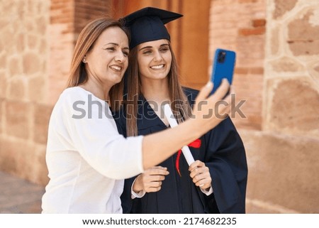 Two women mother and graduated daughter making selfie by smartphone at campus university