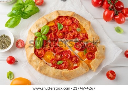 Tomatoes galette or pie with cheese and herbs on a white wooden background. Vegetarian dish. Selective focus Royalty-Free Stock Photo #2174694267