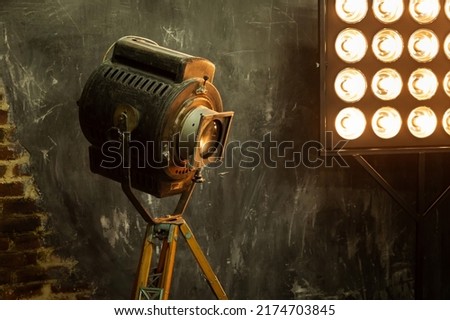 Old retro video spotlight on a stand in the studio for filming movies and photos, a light panel. Grunge vintage loft style in warm colors. Close-up view.