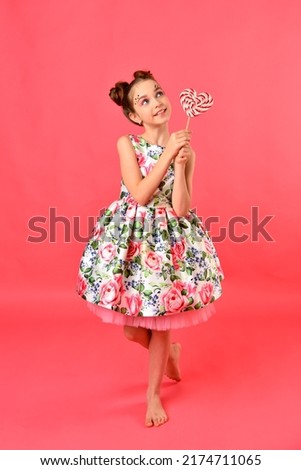 A cute girl with balloons and candy. Pink background. Party.