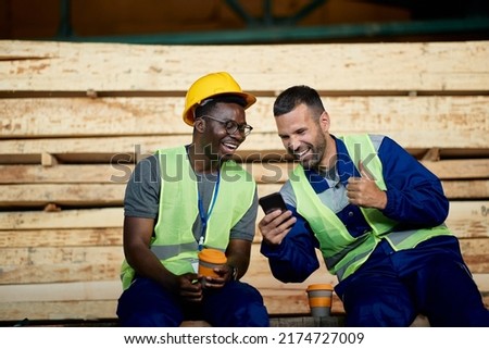 African American worker and his colleague laughing and having fun while using smart phone during their coffee break.  Royalty-Free Stock Photo #2174727009