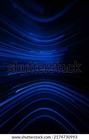 Defocused neon light. Futuristic background. Sci-Fi illumination. Blur luminous navy blue color curve lines flare reflection motion on dark black abstract overlay.