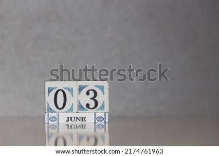 Wooden calendar dated 3 June. Daily calendar block sets for the month. Still life in the home studio with dark background and copy space.
