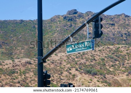 Kanan road sign Agoura Hills California hanging on pole over road with Santa Monica Mountains in background