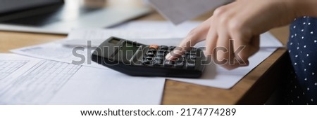 Accounting professional woman counting money, expenses, fees, analyzing bills, financial reports, company budget, using calculator, checking heap of documents, paying taxes. Banner shot, hand close up