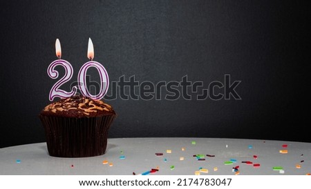 Muffin on black with a number from a candle number 20. Copy space, a pie on a black background, a card for congratulations on your birthday, anniversary Royalty-Free Stock Photo #2174783047