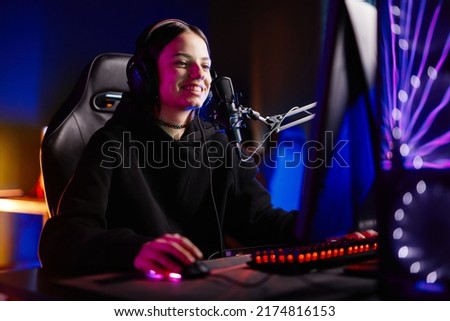 Portrait of female streamer playing video games in dark studio with neon accents