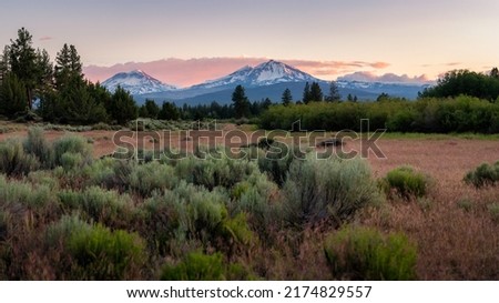 Three Sisters Mountains during sunset in Central Oregon as seen from Sisters, Oregon just outside of Bend in Central Oregon just east of the Cascades and Three Sisters Mountains.  Royalty-Free Stock Photo #2174829557