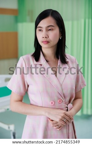 Asian woman patient standing in emergency ward at hospital. Empty hospital bed on background. Healthcare medical and medicine concept.