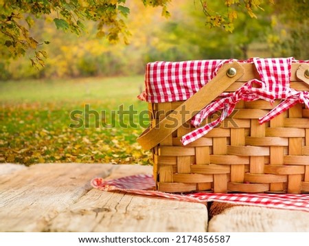 Picnic basket on a wooden table against the background of beautiful autumn nature, golden leaves. Picnic, rest, beauty of nature, ecology, healthy organic food.