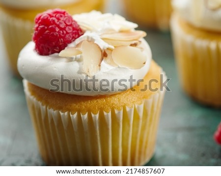 Close-up. Light dessert. Muffin with cream, raspberries and almonds on a green background. Birthday, anniversary, wedding. Banquet, picnic, restaurant, hotel, cafe.