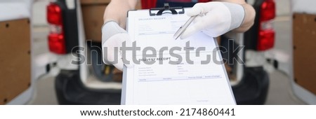 Man in uniform and face mask give delivery receipt paper to receiver to sign