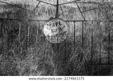 Sign on a fence prohibiting entry. Gate is rusted and yard is filled with grass, home abandoned. Rubyvale Australian gemfields.