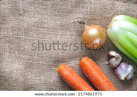 Fresh vegetables in the corner on the matting. Onions, garlic, celery stalks and carrots. Top view, selective focus with copy space