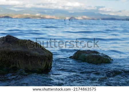 Sunny summer lake views, mountains and cities, rocks on the shore