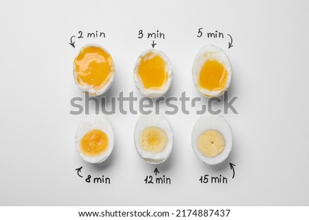 Different cooking time and readiness stages of boiled chicken eggs on white background, flat lay Royalty-Free Stock Photo #2174887437