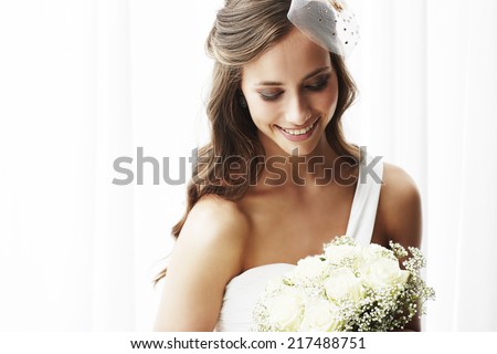 Young bride in wedding dress holding bouquet, studio shot   Royalty-Free Stock Photo #217488751