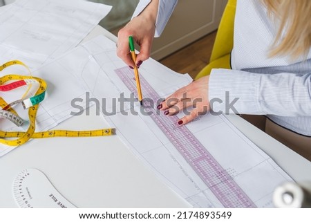 Female designer drawing paper patterns. Exclusive clothes making concept. Workplace of seamstress