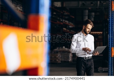 Business man standing at the factory and using laptop Royalty-Free Stock Photo #2174900441
