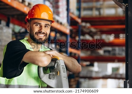 Workman at a factory standing by the pallet jack Royalty-Free Stock Photo #2174900609