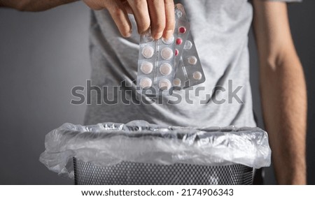 Male hand throws pills into the trash. Royalty-Free Stock Photo #2174906343
