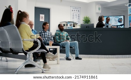 Diverse group of people waiting in hospital reception lobby to attend medical appointment with general practitioner. Patients in waiting room lobby sitting at healthcare clinic. Tripod shot. Royalty-Free Stock Photo #2174911861