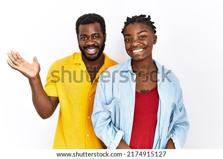 Young african american couple wearing casual clothes smiling cheerful presenting and pointing with palm of hand looking at the camera. 