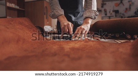 Tailor cobbler hold different rolls natural brown leather, working with textile in workshop. Royalty-Free Stock Photo #2174919279