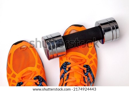 Worn, holey sneakers with protruding toes and a metal dumbbell dropped on the foot, isolated on a white background. Daily wear and safety exercises