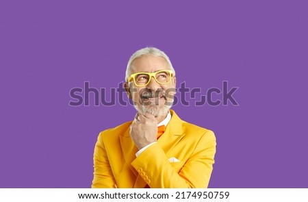 Dreamy delighted elderly man look up empty space, stand in contemplation thinking, isolated on purple color studio background. Handsome wealthy caucasian male in stylish yellow suit. Business people Royalty-Free Stock Photo #2174950759