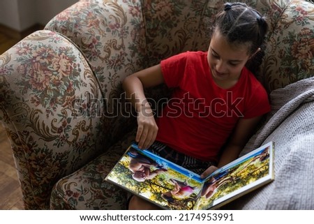 A Little Caucasian girl holding a photobook with her photographs in her hands