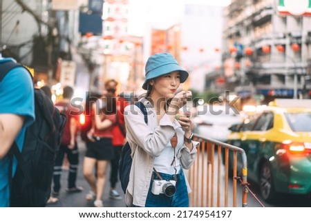 Happy young adult asian foodie woman backpack traveller eating asia dessert. People traveling with lifestyle outdoor at China town street food market. Bangkok, Thailand Royalty-Free Stock Photo #2174954197
