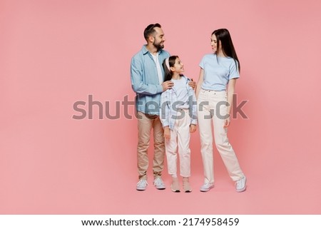 Full body young happy caucasian smiling fun cool parents mom dad with child kid daughter teen girl in blue clothes look to each other isolated on plain pastel light pink background. Family day concept
